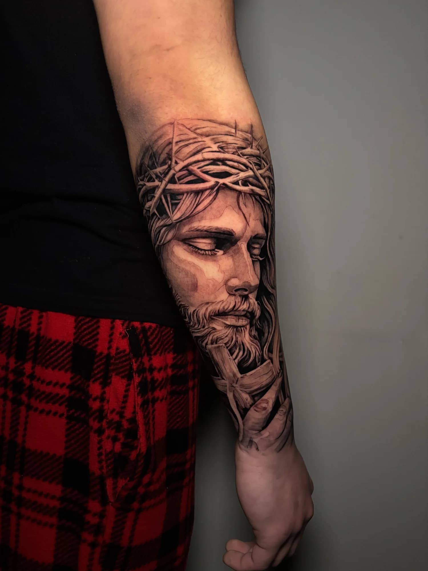 Large black and grey portrait of Christ with a crown of thorns on the forearm