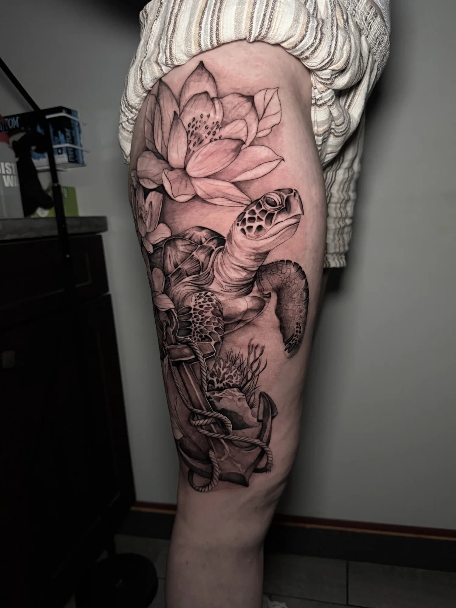 Large black and grey sea turtle and lotus tattoo on the outer thigh