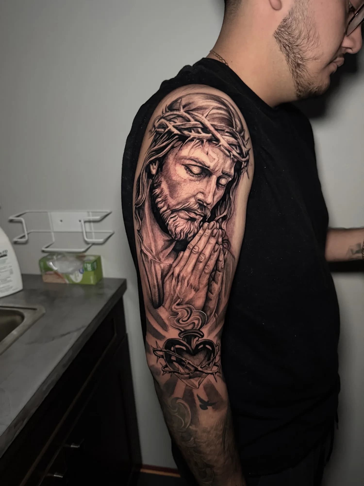 Large black and grey praying Christ portrait sleeve covering the arm