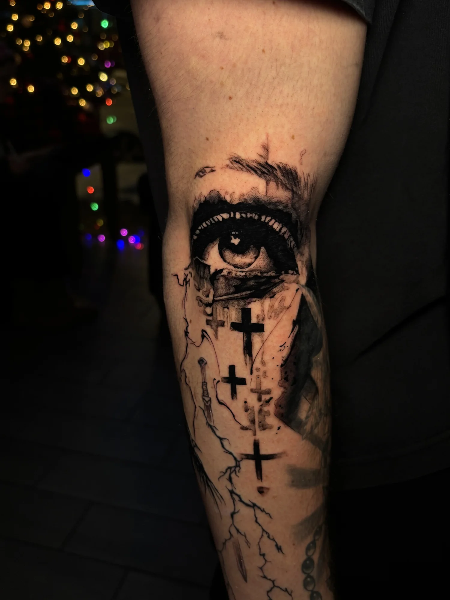 Fine-line blackwork eye and crosses tattoo on the forearm